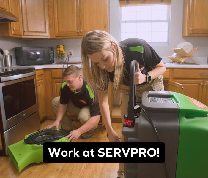 Two SERVPRO Technicians working together to clean up some water damage in a kitchen